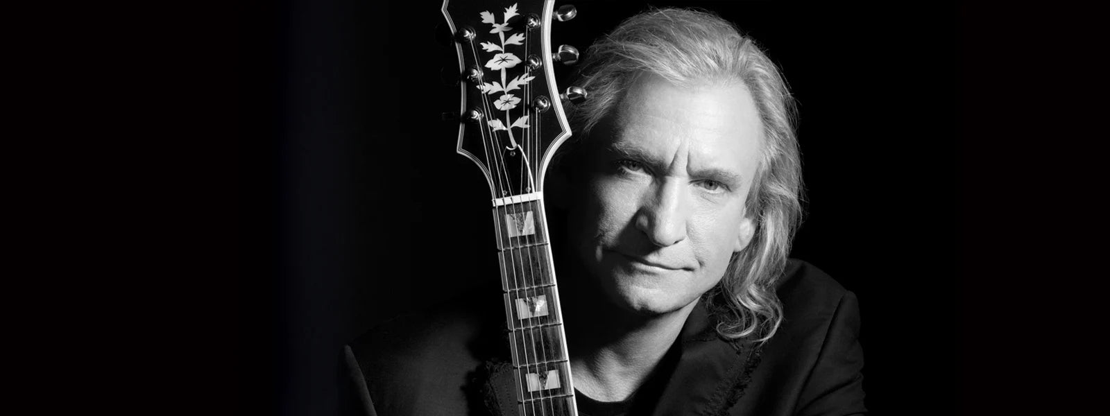 Black and white photo of Joe Walsh posing with guitar